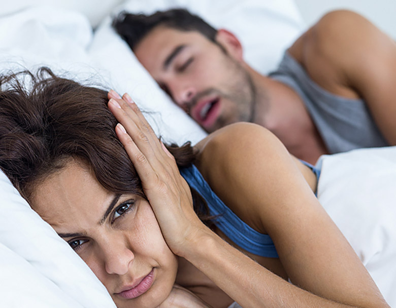 Woman covering ears from snoring partner