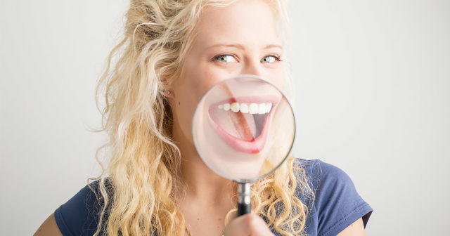 Woman with a magnifying glass over her open mouth, smiling