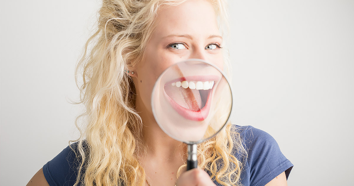 Woman with a magnifying glass over her open mouth, smiling