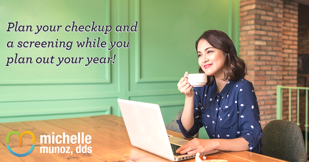 woman drinking coffee and smiling at table with laptop